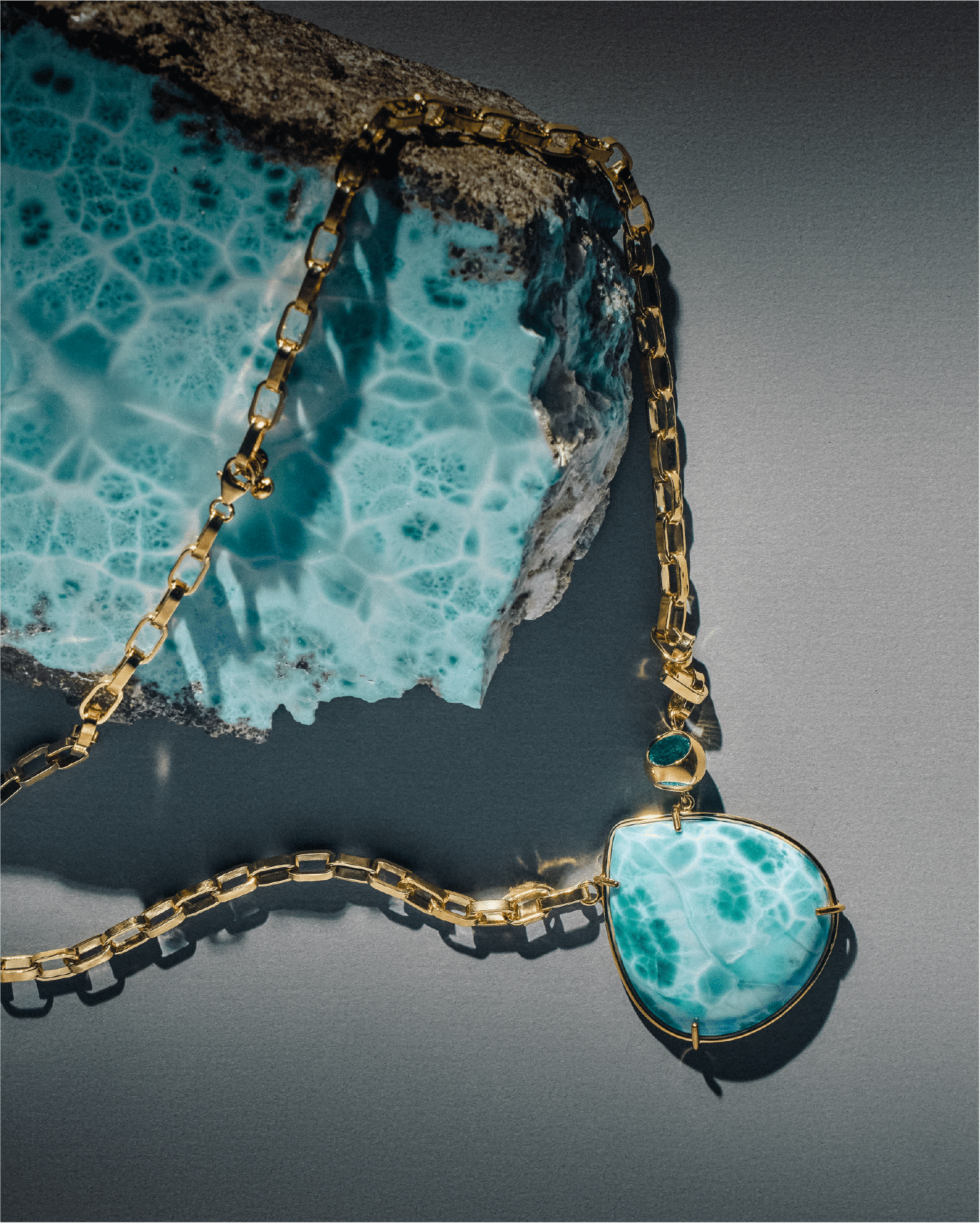 Raw larimar stone with a larimar pendant on a gold chain