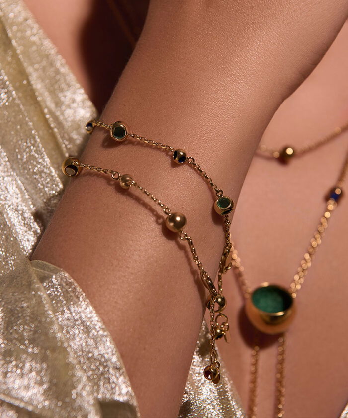 Delicate gold chain necklace featuring small beads and green gemstone accents for a chic look.