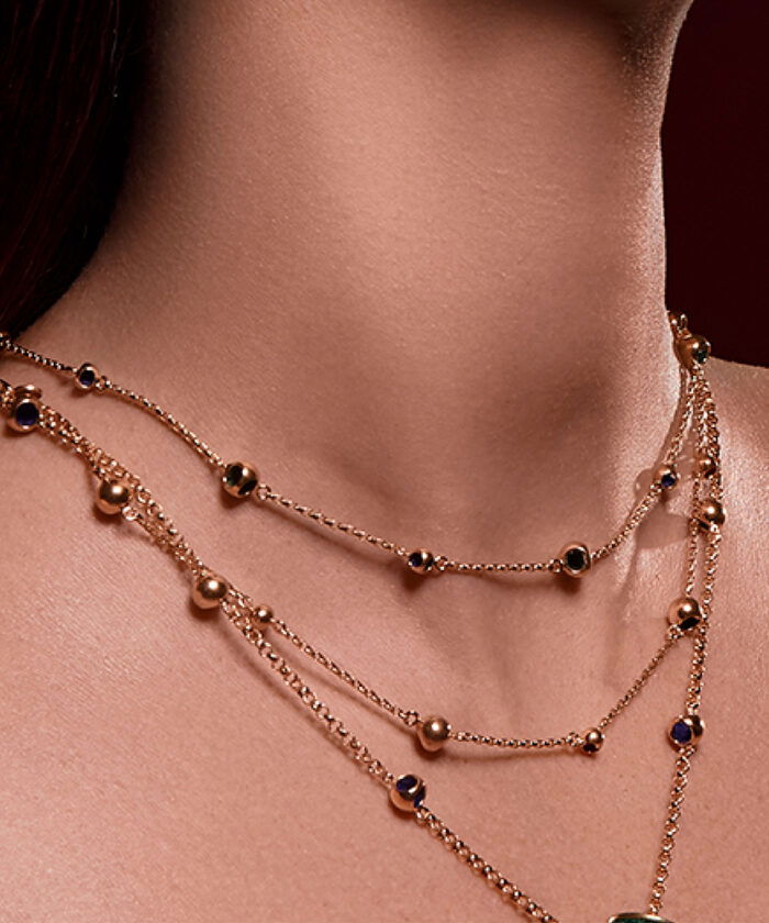 Elegant layered gold necklace with black and blue gemstone accents, perfect for stylish occasions.