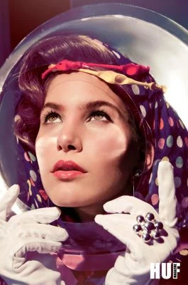 Close-up of Monica Varela in vintage astronaut helmet, elegant makeup, and polka-dot headscarf.