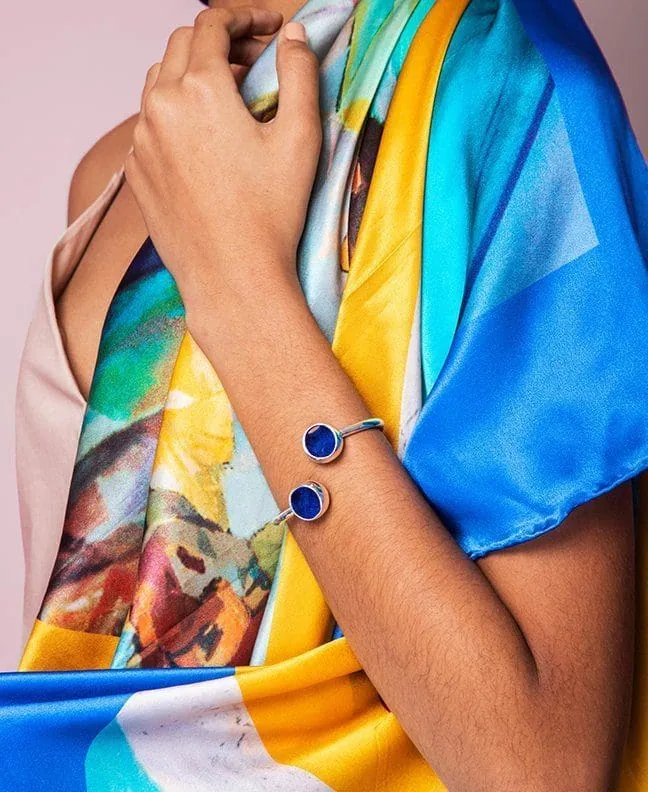 Elegant blue cuff bracelet paired with a multicolor silk scarf, perfect for chic fashion statements.