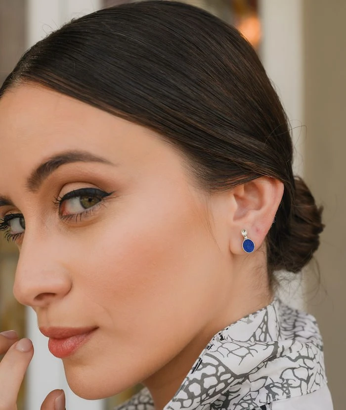Close-up of a beautiful woman with brown hair, green eyes, and elegant makeup, highlighting jewelry.