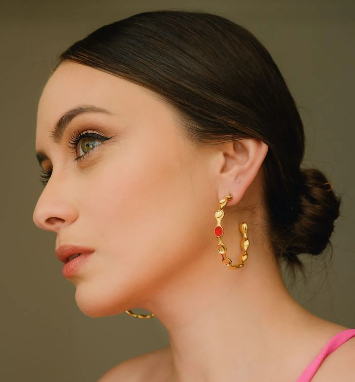 Elegant gold hoop earrings with colorful accents in a close-up portrait.