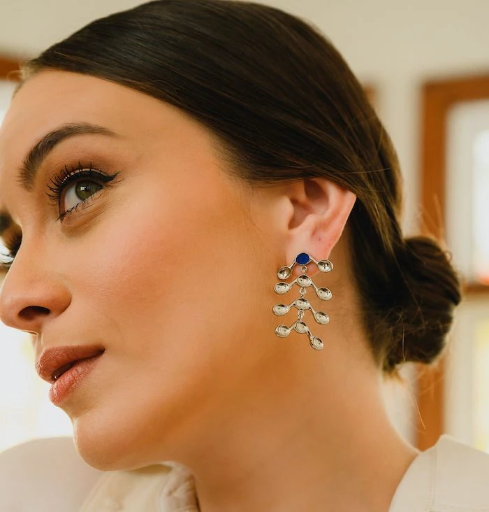 Beautiful woman wearing silver venule earrings with dangling elements, perfect for sophisticated style.