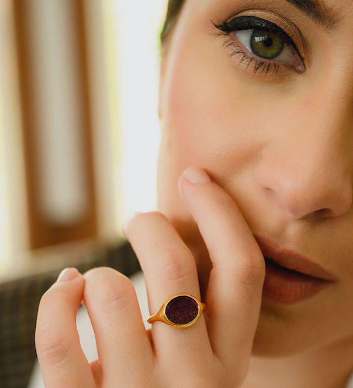 Close-up of woman's hand showcasing a stylish gold ring with a dark gemstone.