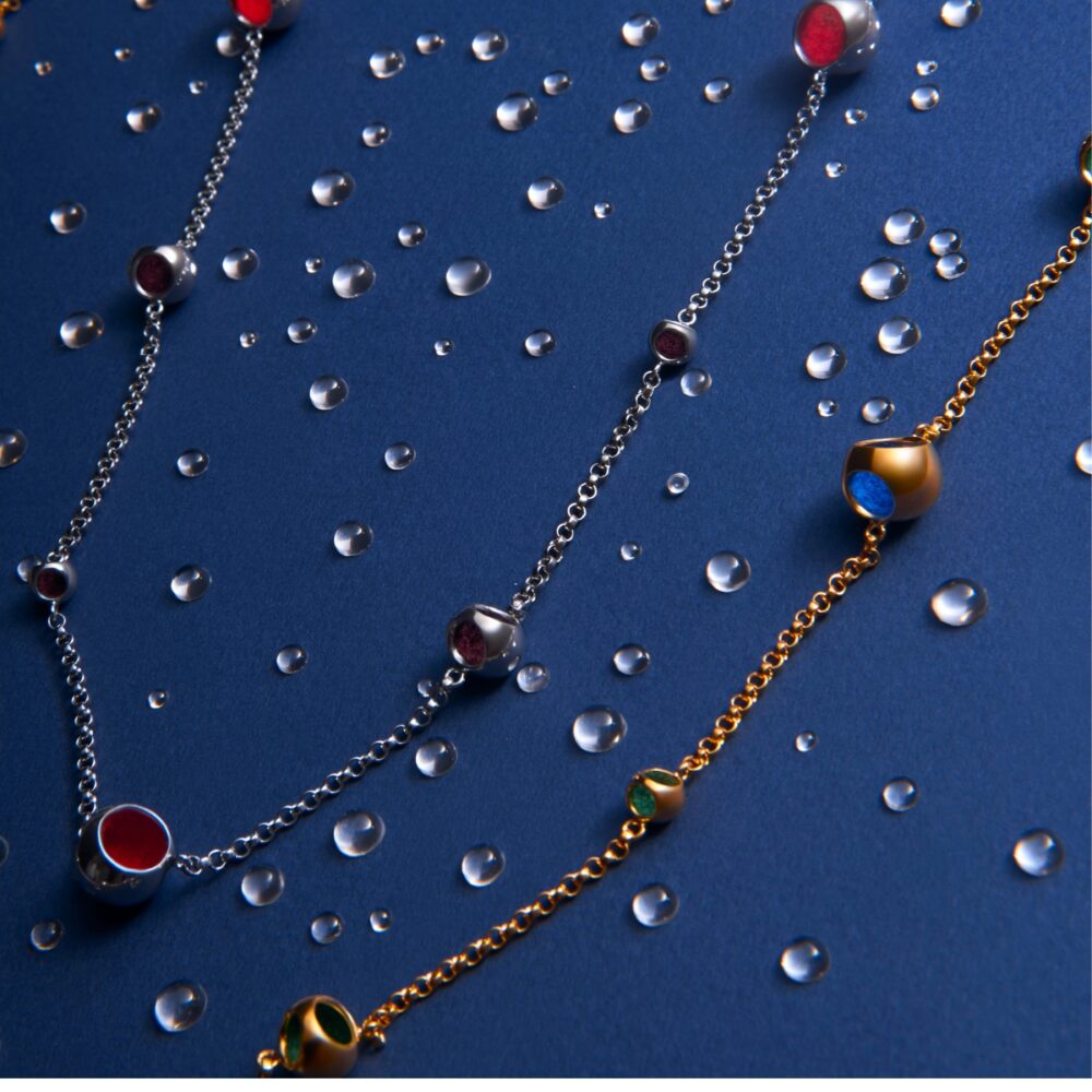 Elegant silver and gold necklaces with colorful gemstone accents on a blue background. Perfect for stylish accessorizing.