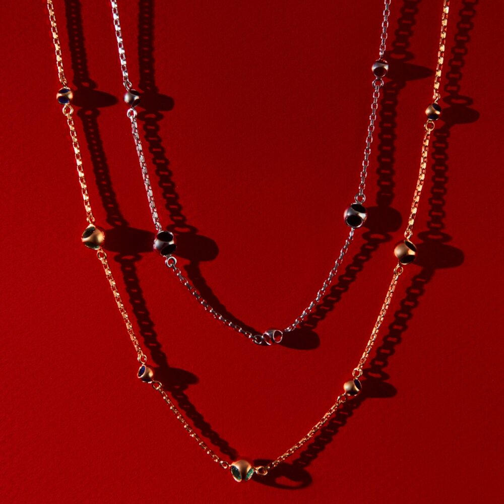 Elegant layered necklaces with black bead accents against a red background.