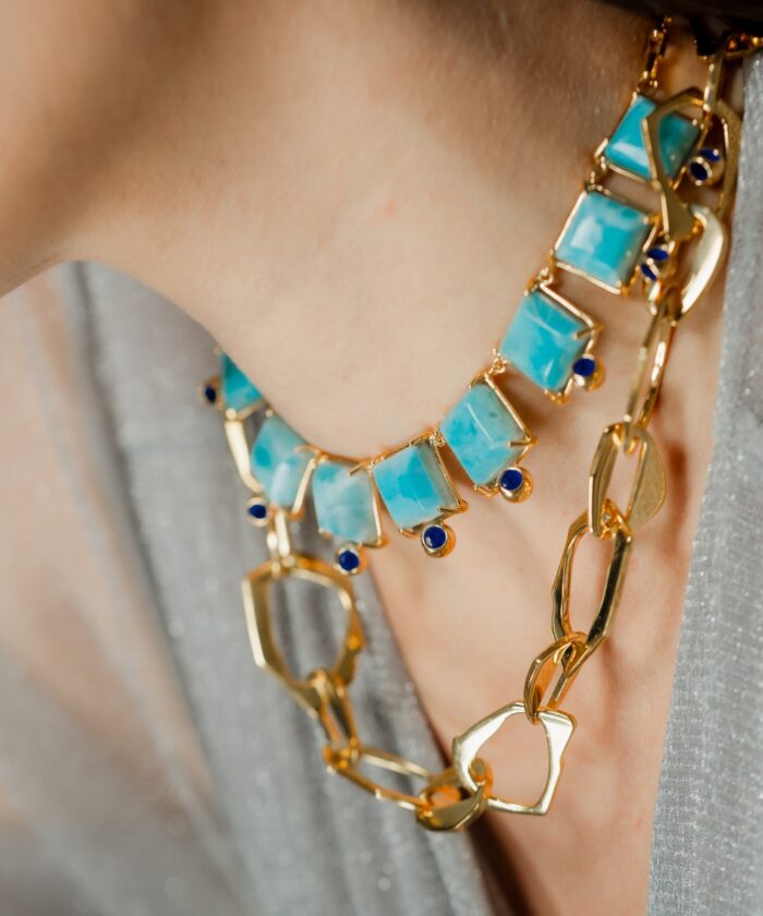Stunning turquoise and gold chain necklace featuring geometric and heart-shaped charms for a chic style.
