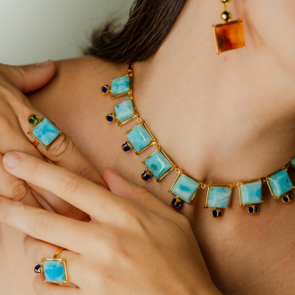 Bright blue Larimar necklace, earrings, and ring featuring gold and sapphire accents, perfect for stylish accessorizing.