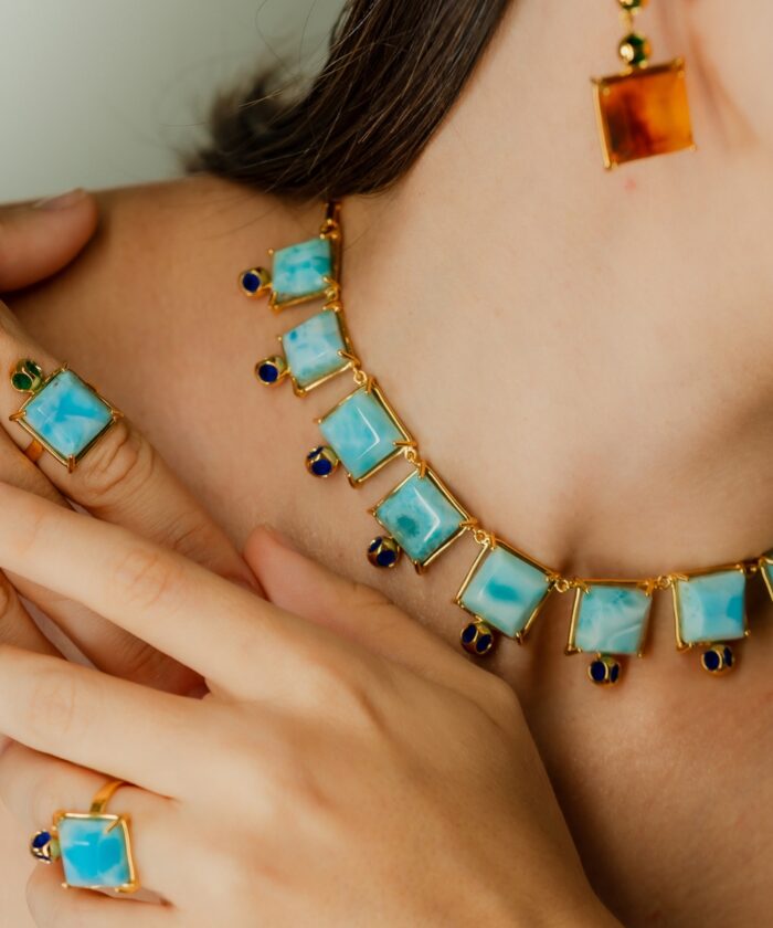 Bright blue Larimar necklace, earrings, and ring featuring gold and sapphire accents, perfect for stylish accessorizing.