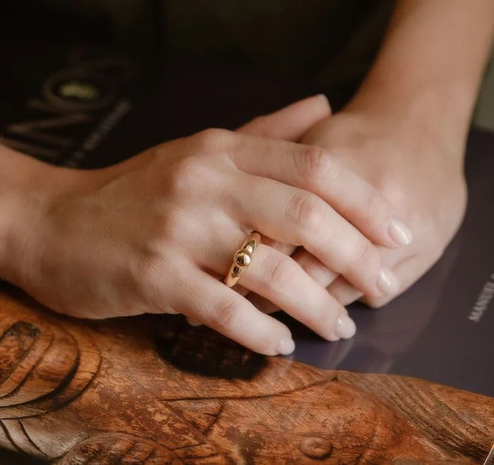 Stunning gold ring featuring droplet design on a woman’s finger, stylish jewelry accessory.