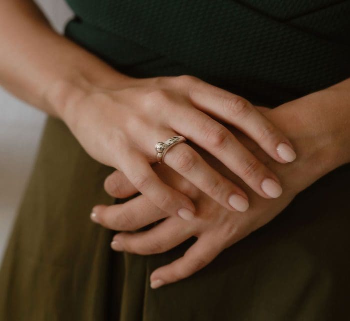 Elegant silver droplet ring on woman's finger, close-up jewelry shot.