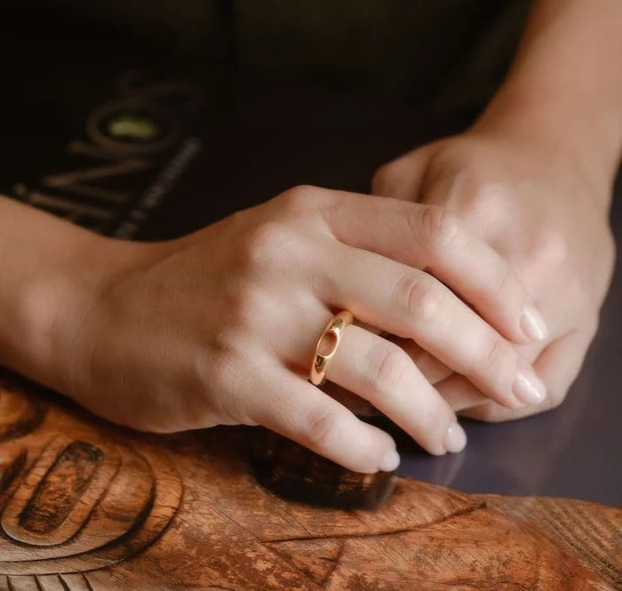 Elegant gold ring on finger, close-up shot.