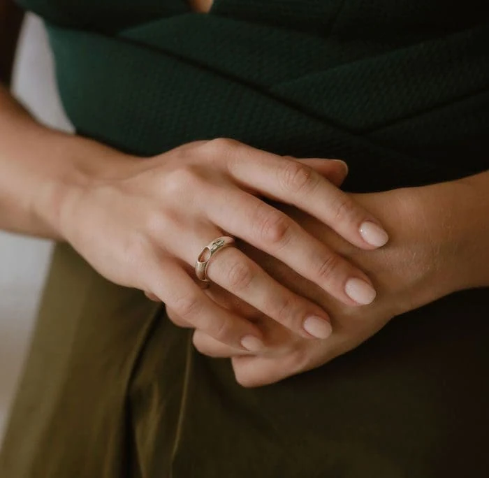 Close-up of a woman wearing a sleek, dropless wedding ring on her hand, showcasing modern jewelry style.