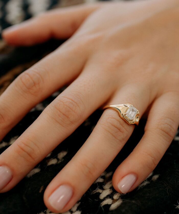 Close-up of diamond cut ring on a woman's finger, showcasing fine jewelry craftsmanship.