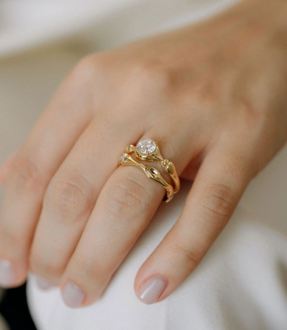 Close-up of a sterling gold cloud-shaped ring with sparkling diamonds, worn on a woman's finger.