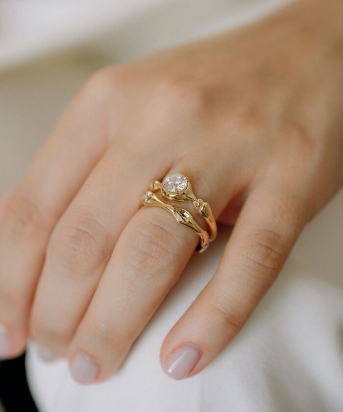 Close-up of a sterling gold cloud-shaped ring with sparkling diamonds, worn on a woman's finger.