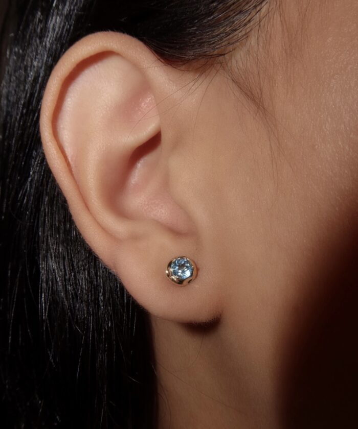 Small blue topaz stud earrings in a sleek gold setting, perfect for everyday wear and special occasions.