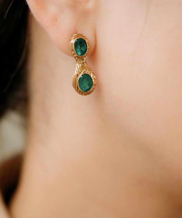 Gold earrings with striking green emerald stones, perfect for a stylish and sophisticated look.