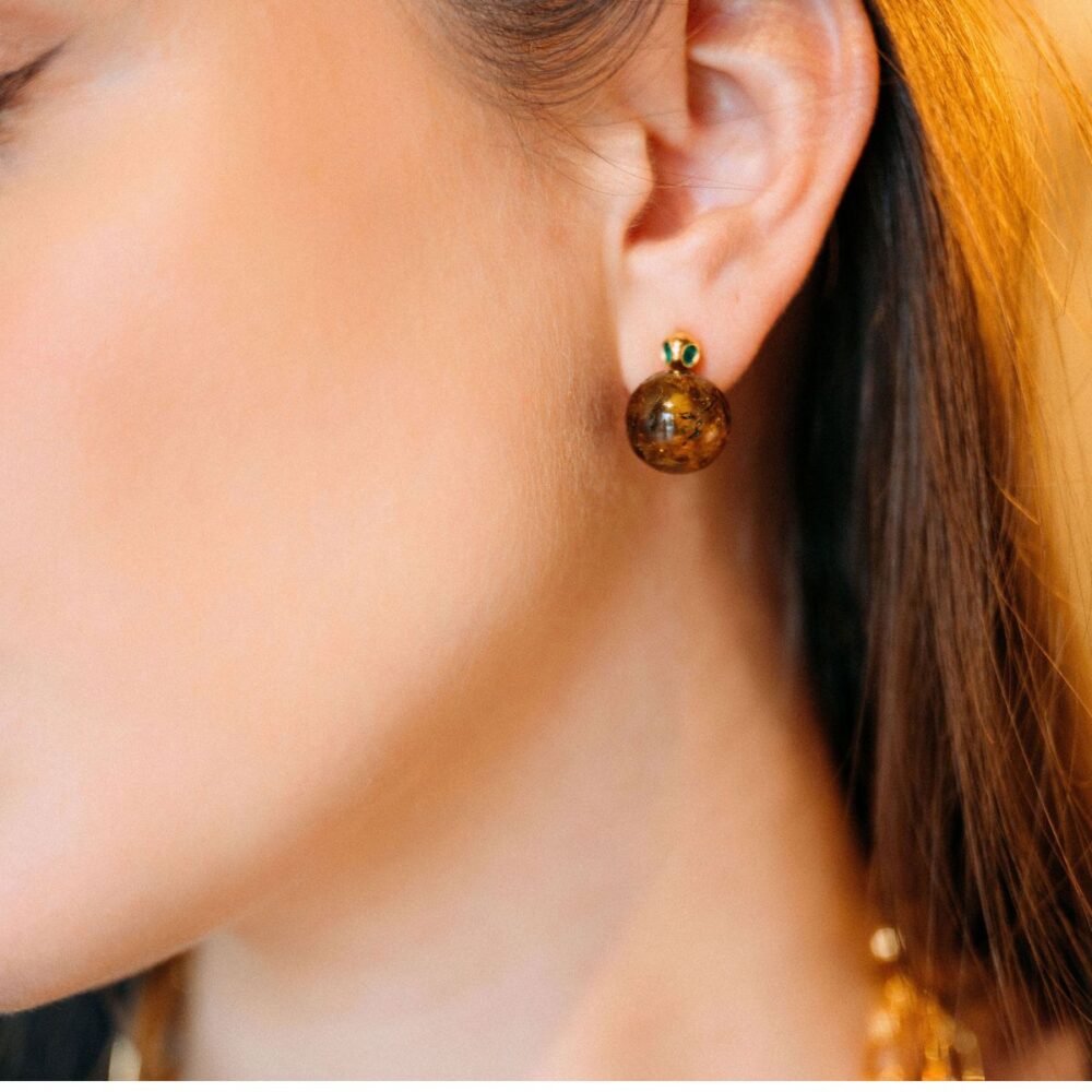 Close-up of a woman's ear showcasing Tiffany-style amber stud earrings.