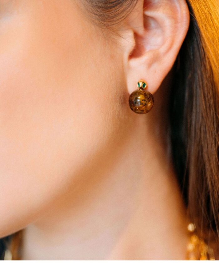 Close-up of a woman's ear showcasing Tiffany-style amber stud earrings.