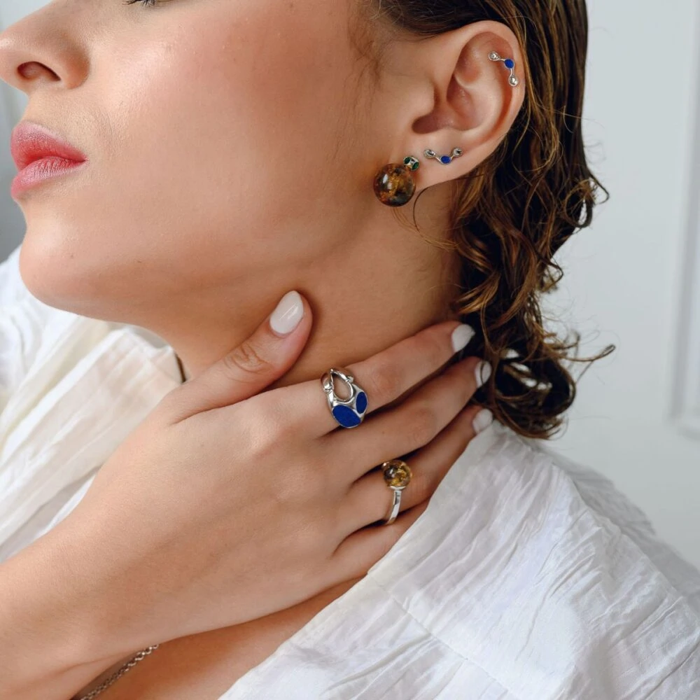 Delicate amber and sapphire stud earrings styled with multiple piercings and matching jewelry. Perfect for sophisticated looks.