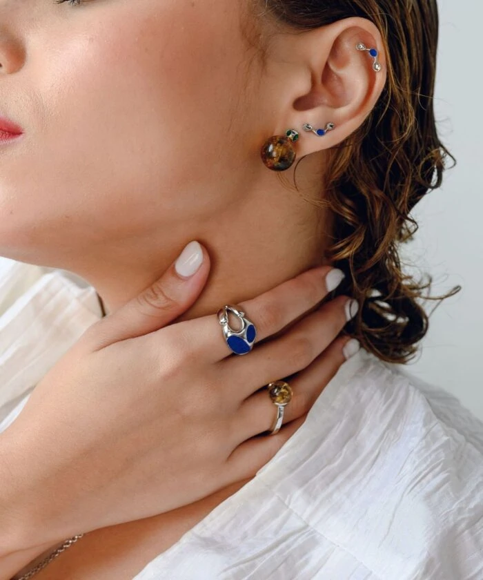 Delicate amber and sapphire stud earrings styled with multiple piercings and matching jewelry. Perfect for sophisticated looks.