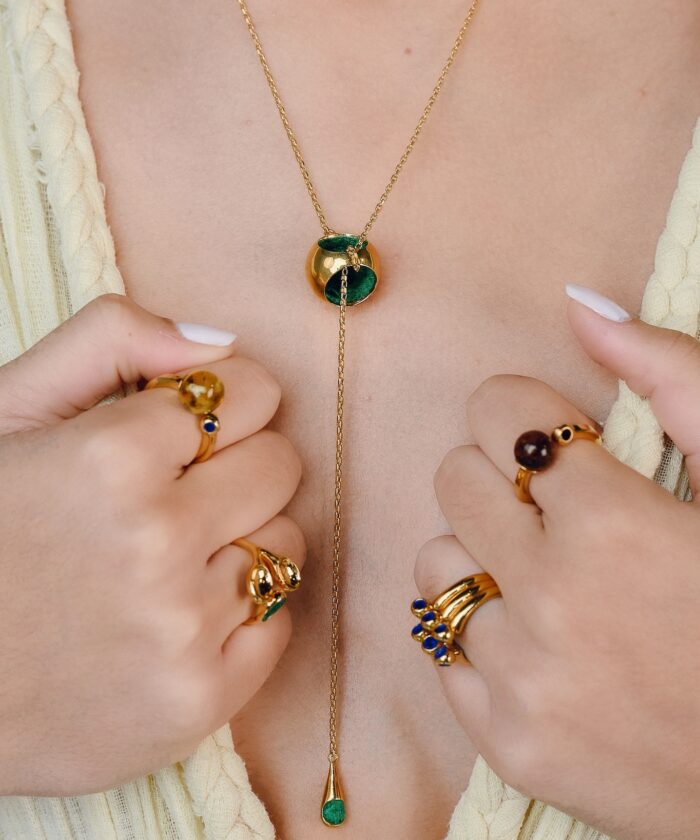 Stunning gold jewelry featuring green and brown stones, including rings and a necklace with a stylish knot T-necklace design.