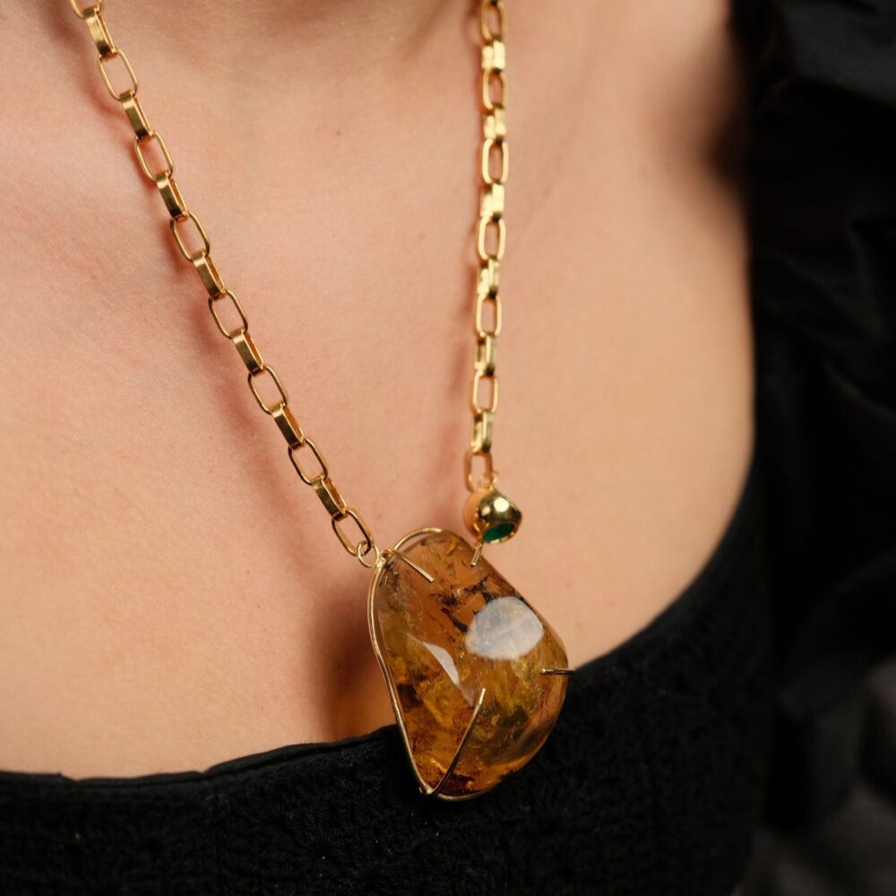 Elegant gold chain with amber pendant and green accent bead. Perfect statement jewelry piece for any outfit.