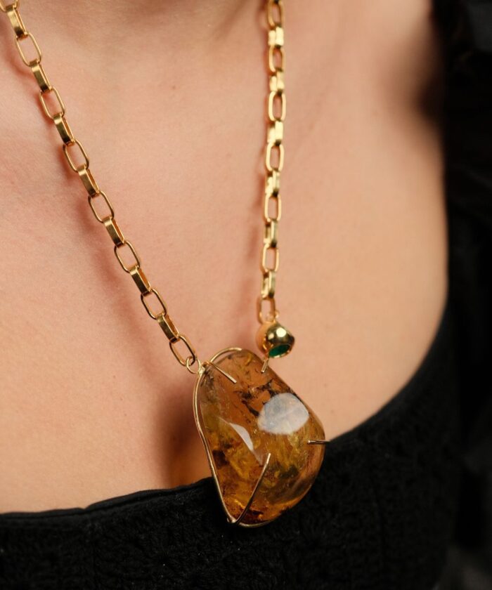 Elegant gold chain with amber pendant and green accent bead. Perfect statement jewelry piece for any outfit.