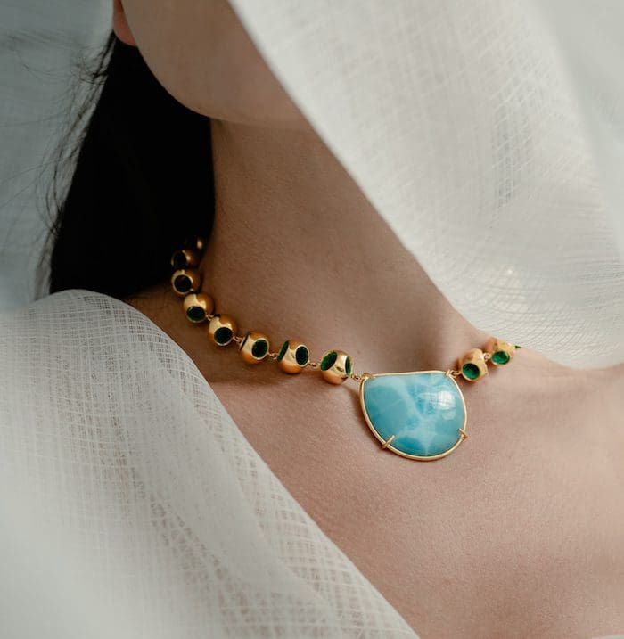 Elegant Larimar necklace with gold and green accents, perfect for sophisticated fashion.