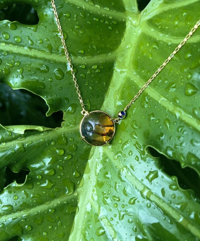Amber pendant with gold-tone chain and blue gemstone accents, stylish jewelry for women.