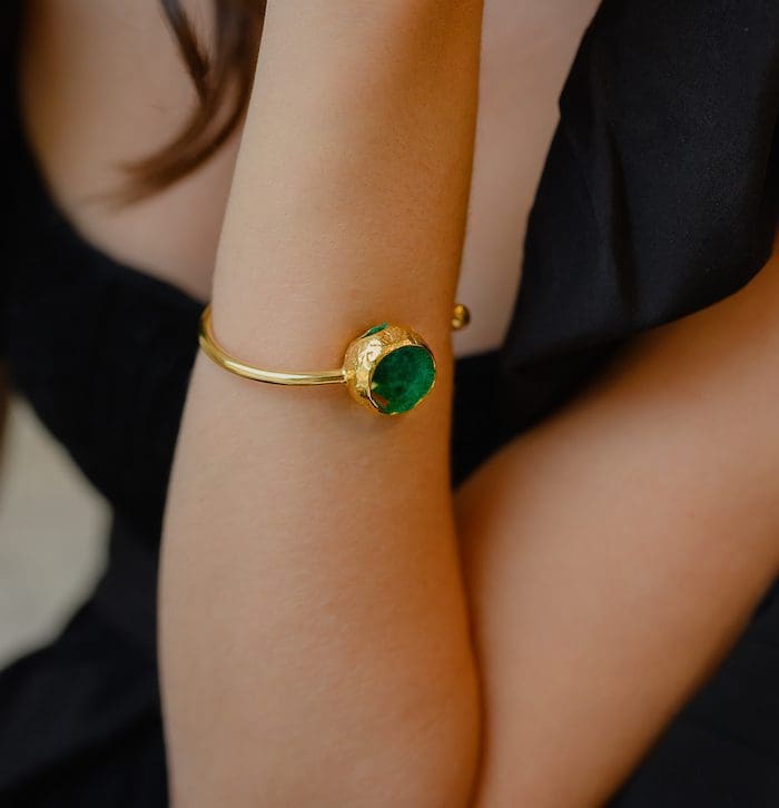 Gold bangle bracelet with a striking green gemstone accent. Perfect jewelry for luxury style statements.