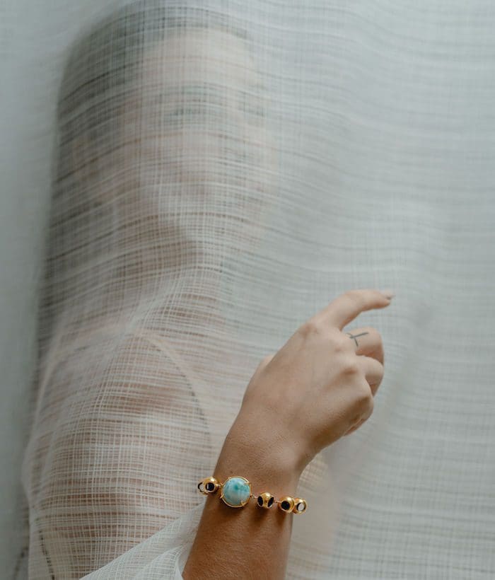 A woman wears a stunning turquoise and black bead bracelet, showcasing luxury jewelry styling. Perfect for fashion-forward accessories.