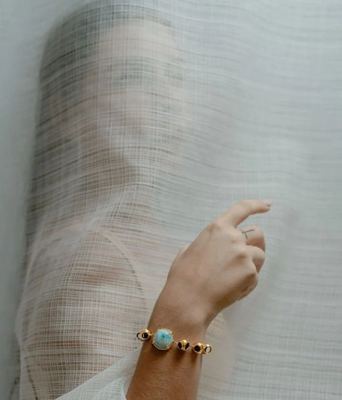 A woman wears a stunning turquoise and black bead bracelet, showcasing luxury jewelry styling. Perfect for fashion-forward accessories.