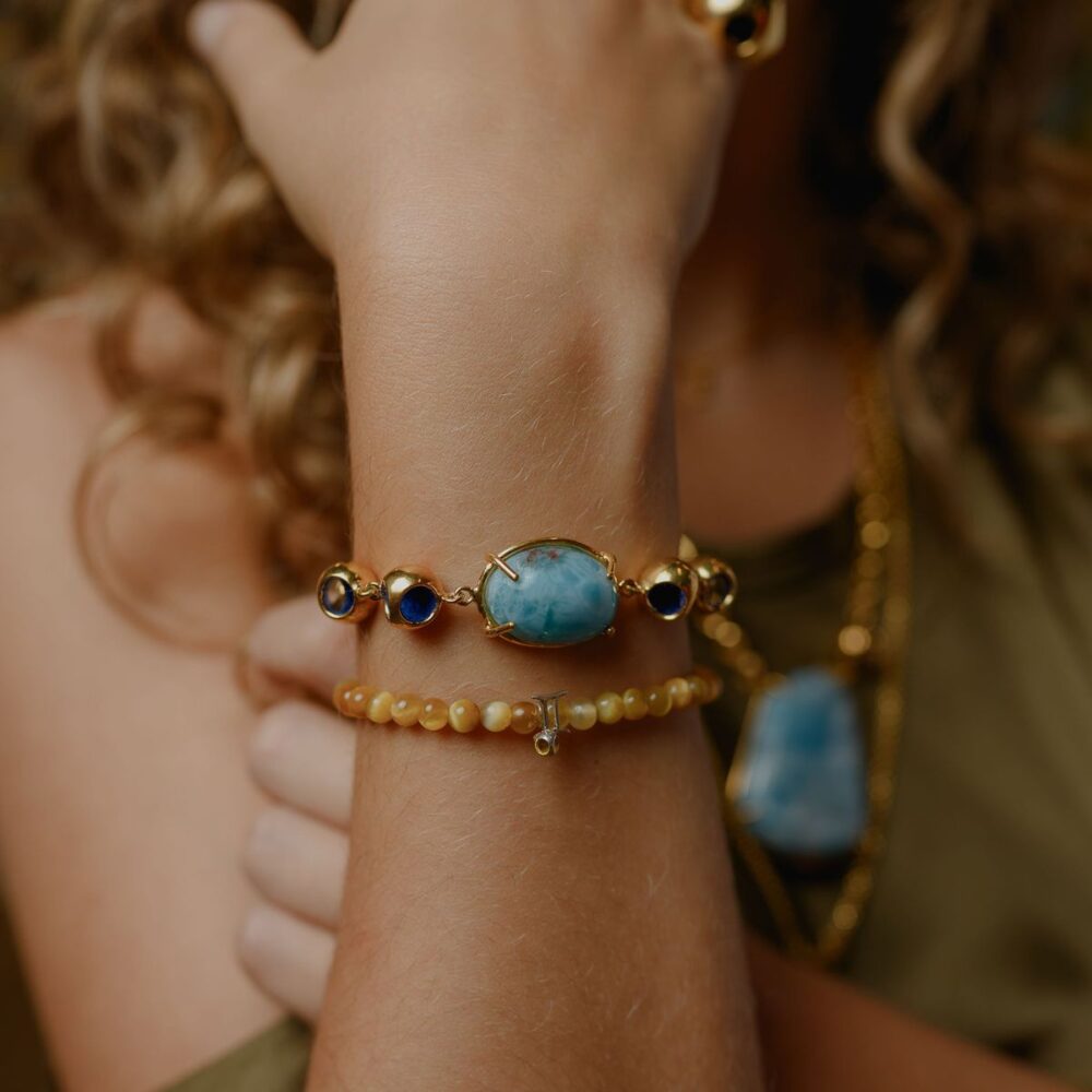 Delicate larimar and navy gemstone bracelet on a woman's wrist showcasing jewelry beauty.