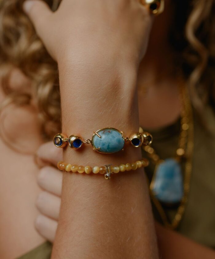 Delicate larimar and navy gemstone bracelet on a woman's wrist showcasing jewelry beauty.