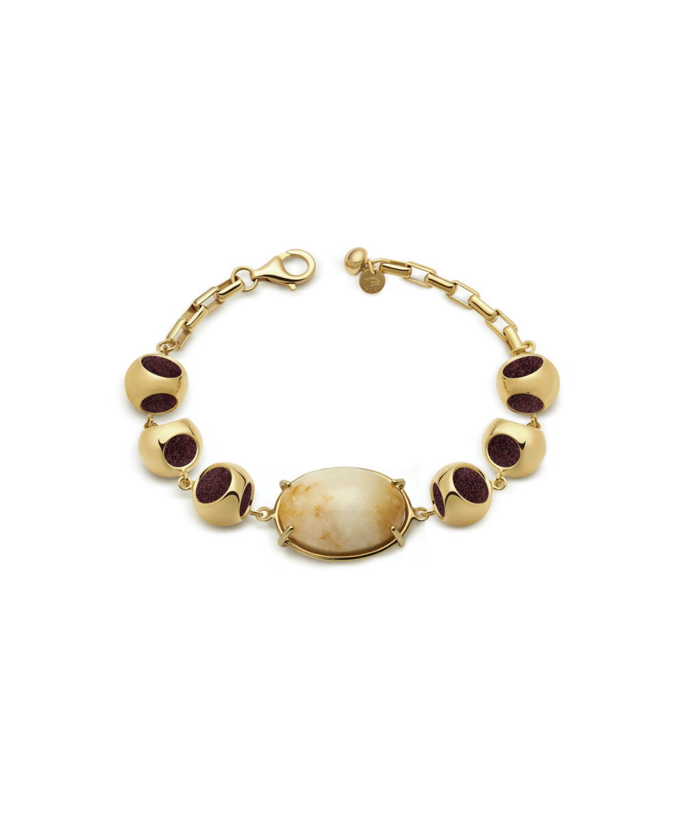 Delicate gold bracelet featuring a stunning moonstone centerpiece and deep red accent beads. Perfect for stylish accessorizing.