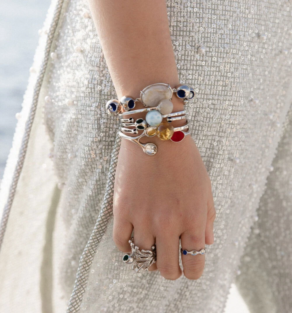 Elegant moonstone bracelet and stacking rings on woman's hand, stylish jewelry, woman wearing trendy accessories.