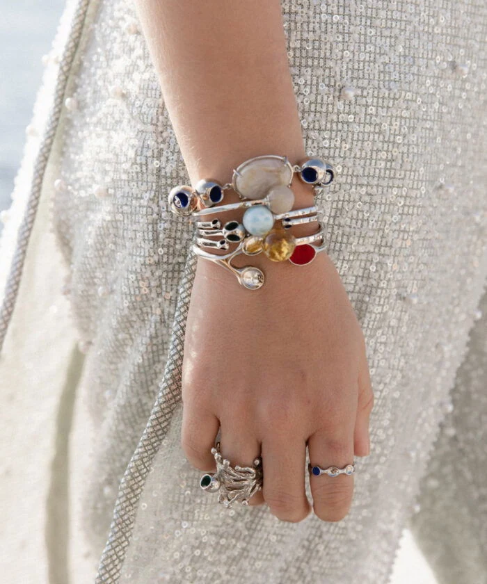 Elegant moonstone bracelet and stacking rings on woman's hand, stylish jewelry, woman wearing trendy accessories.