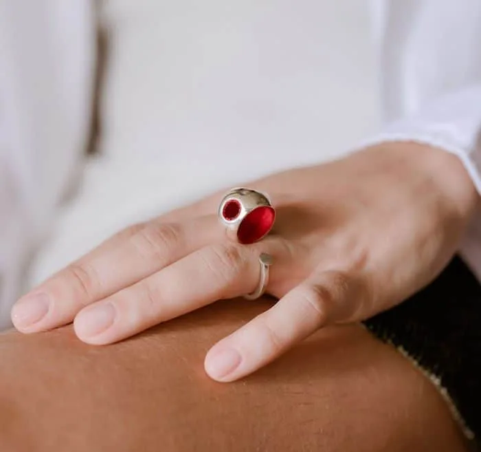Close-up of a stylish ring with red gemstone worn by Monica Varela for elegant jewelry look.