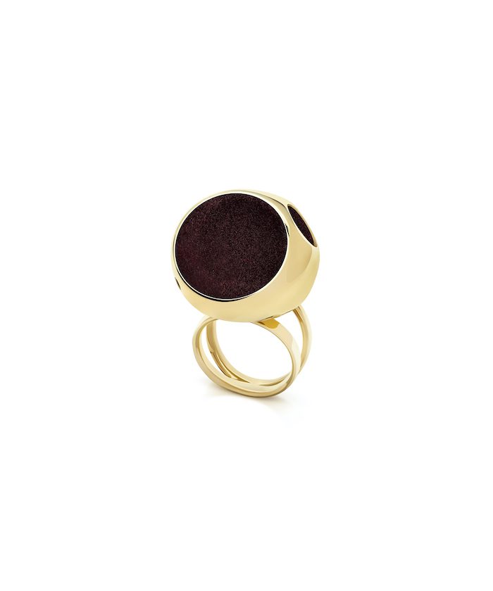 Large gold cocktail ring with black circular centerpiece, stylish statement jewelry piece.
