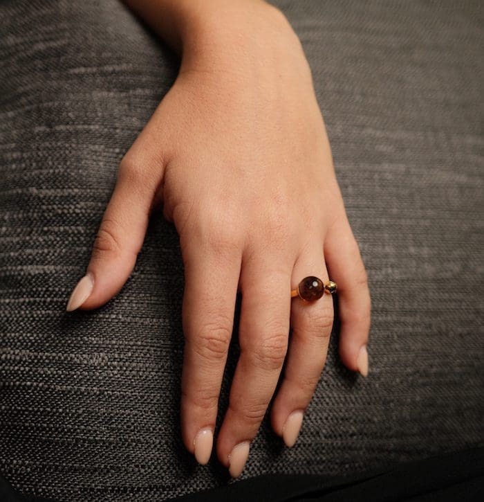 Close-up of a woman's hand wearing a teeny amber ring on her finger.