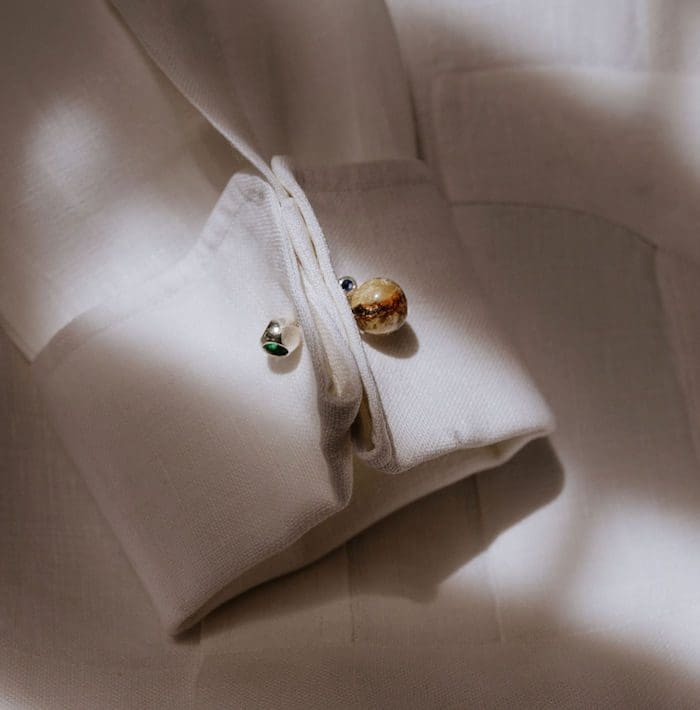 Elegant amber and silver cufflinks on white shirt fabric, stylish for formal occasions.