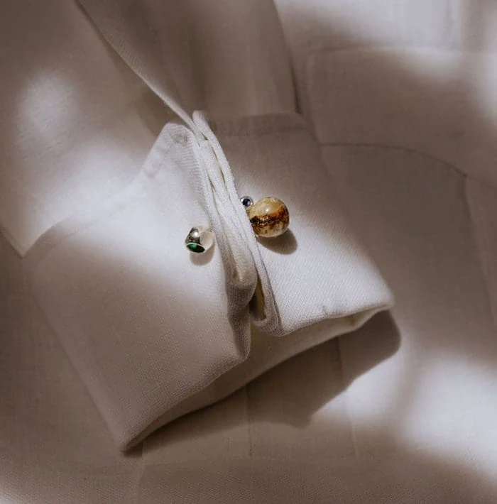 Elegant amber and silver cufflinks on white shirt fabric, stylish for formal occasions.