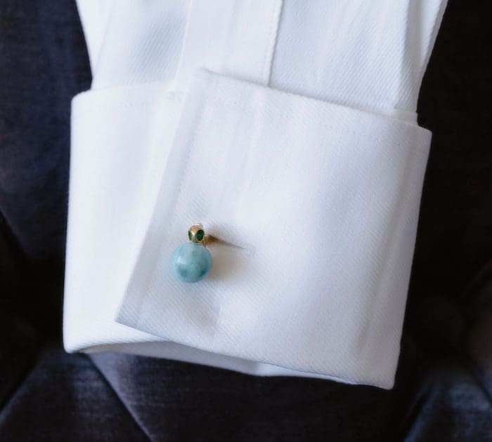 Larimar cufflink featuring a blue-green larimar gemstone in a gold setting on white dress shirt.