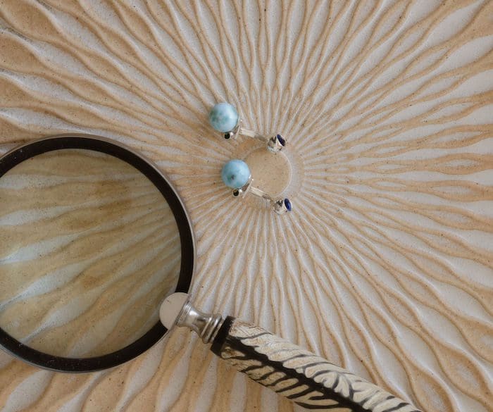 Larimar cufflinks featuring beautiful blue gemstone, paired with jewelry magnifying glass for detailed view.