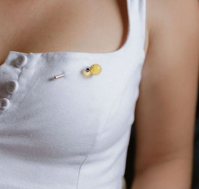 Amber pin on white dress, decorative accessory for fashion or special occasions.