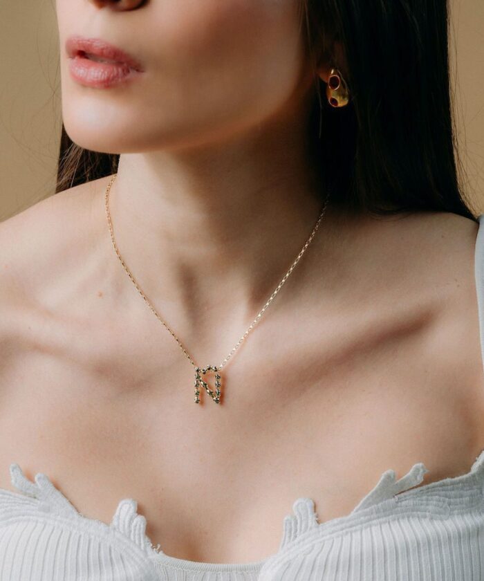 Close-up of Monica Varela wearing gold jewelry, stylish necklace, and earrings.