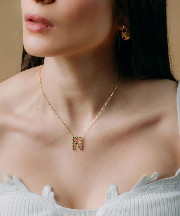 Close-up of Monica Varela wearing gold jewelry, stylish necklace, and earrings.